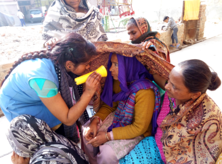 Operation Eyesight trained Community Health Worker screening a woman's eyes in her community