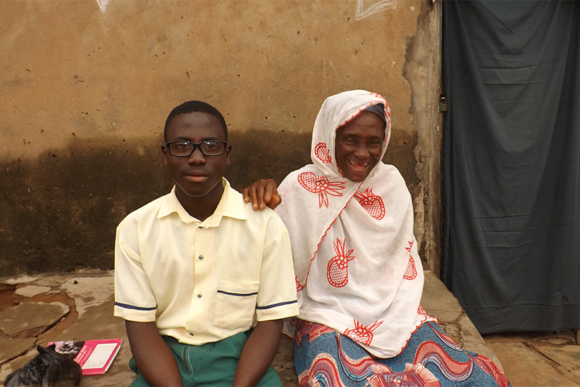 Woman sitting next to her grandson wearing eye-glasses.
