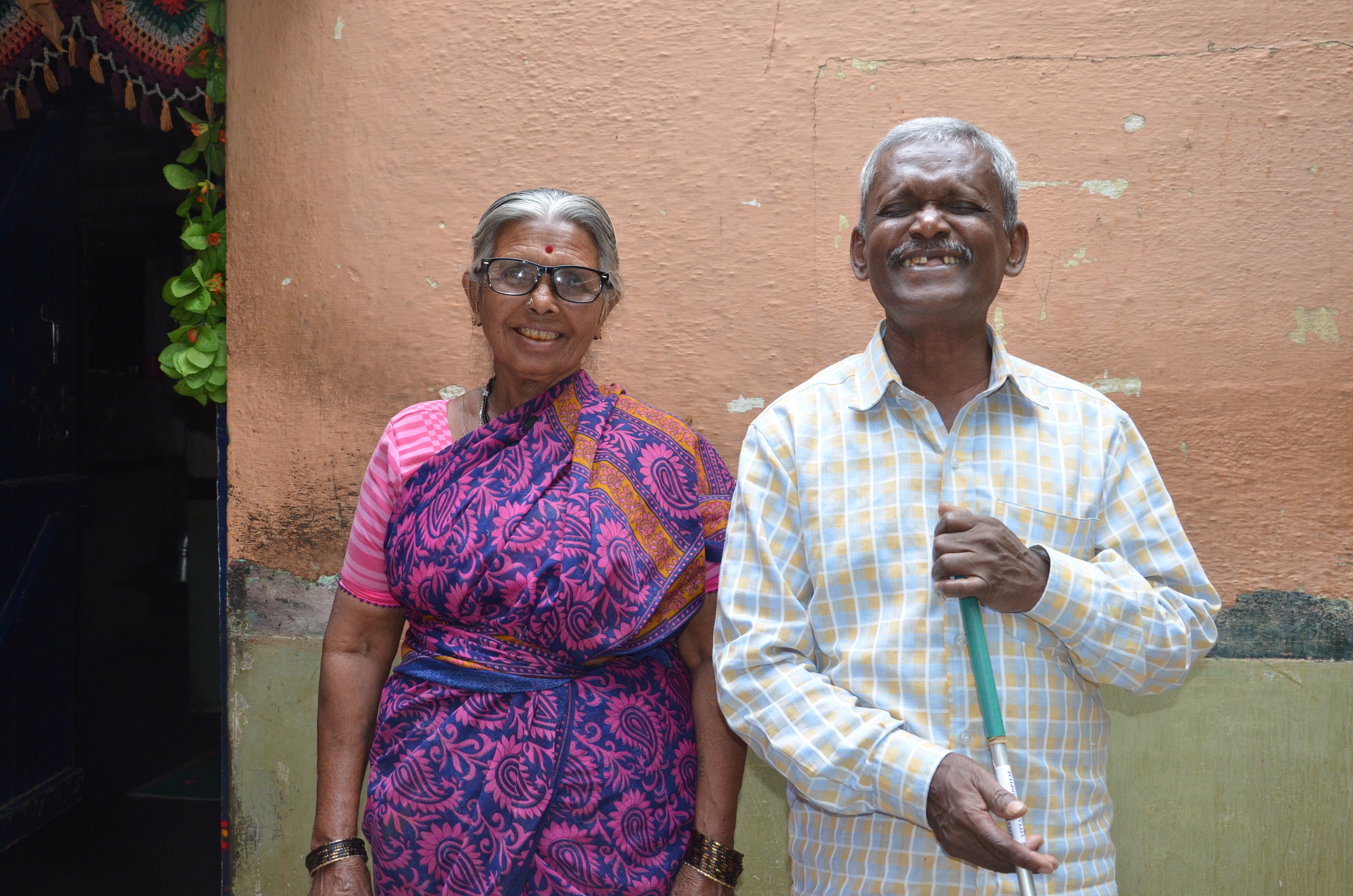 Portrait of man and woman smiling, woman is wearing eyeglasses.