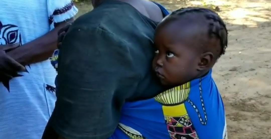 A young child shyly turns away when greeted