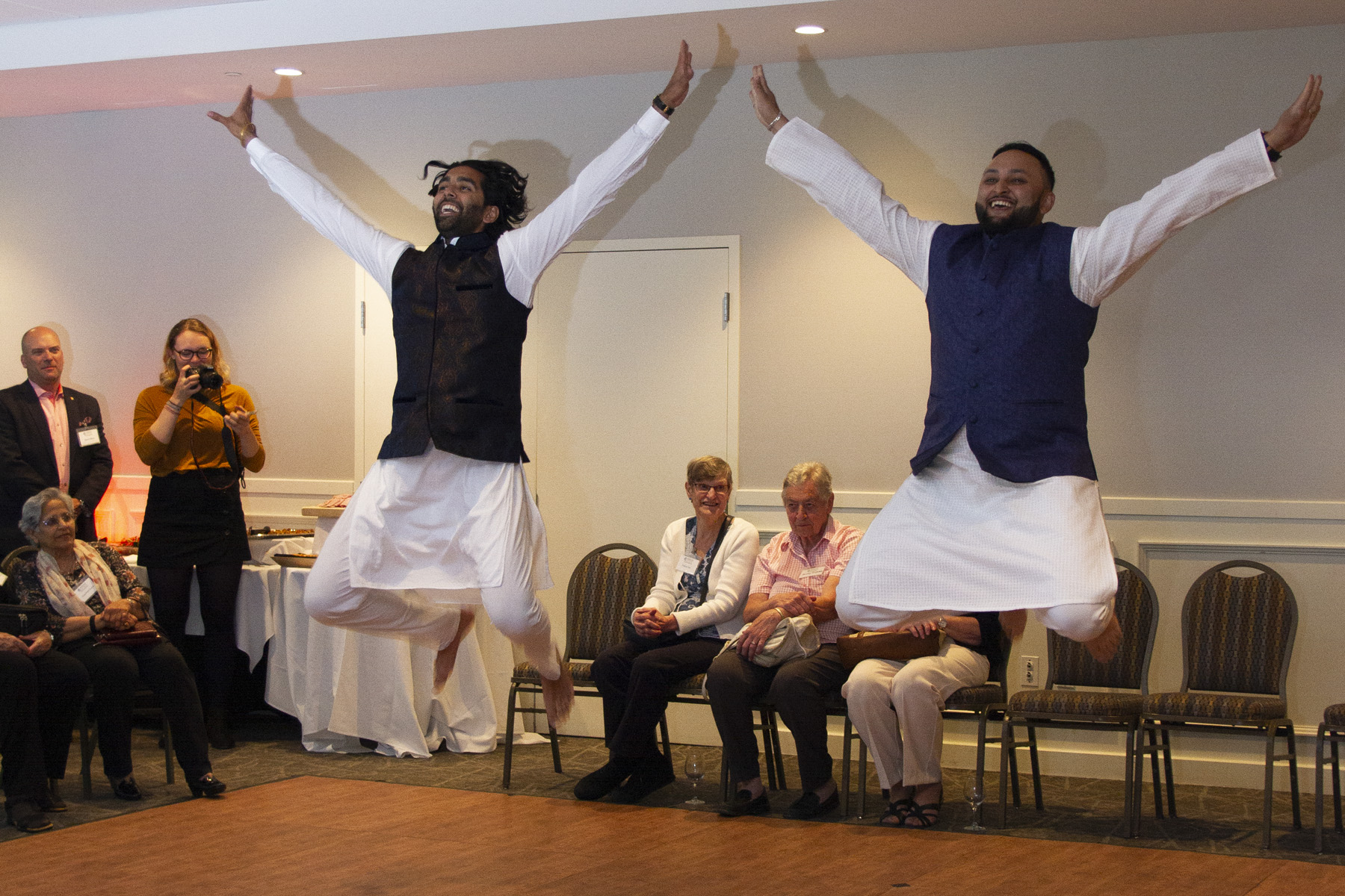 Two men dancing jumping in the air together.