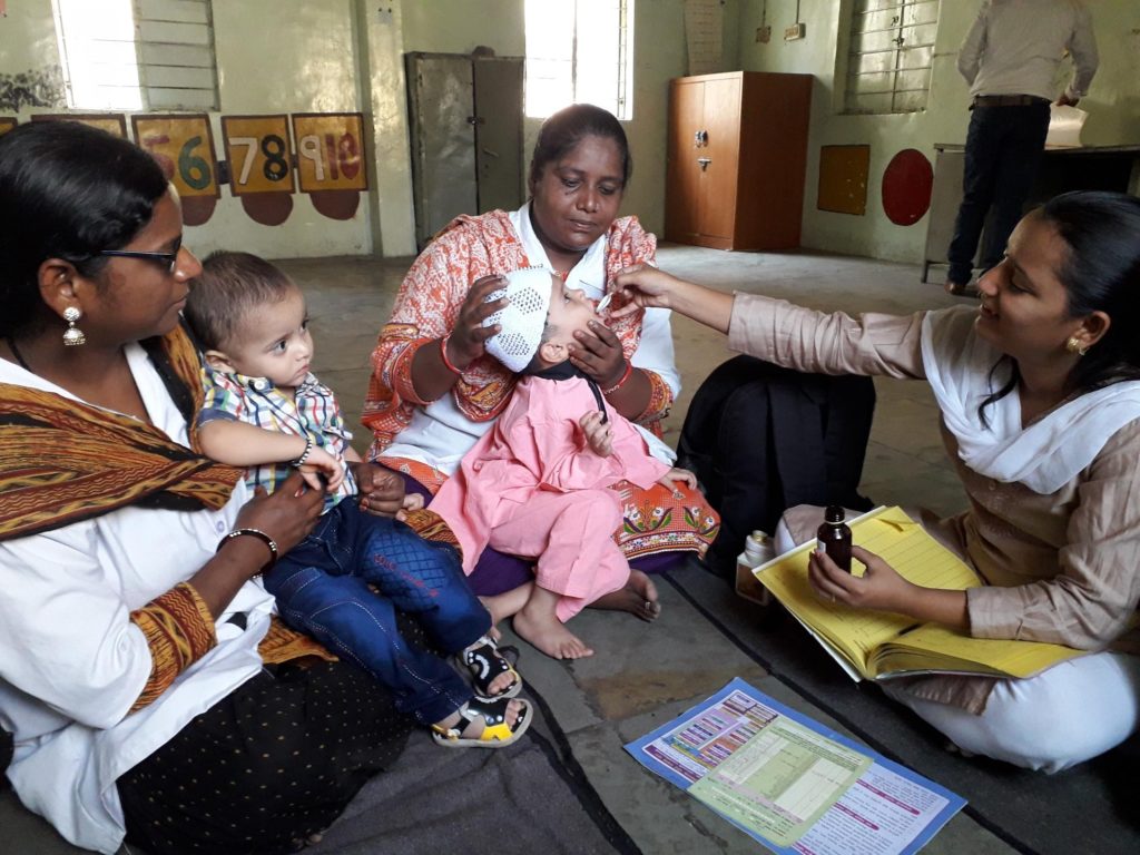 nurses administer vitamin A supplements to child in India