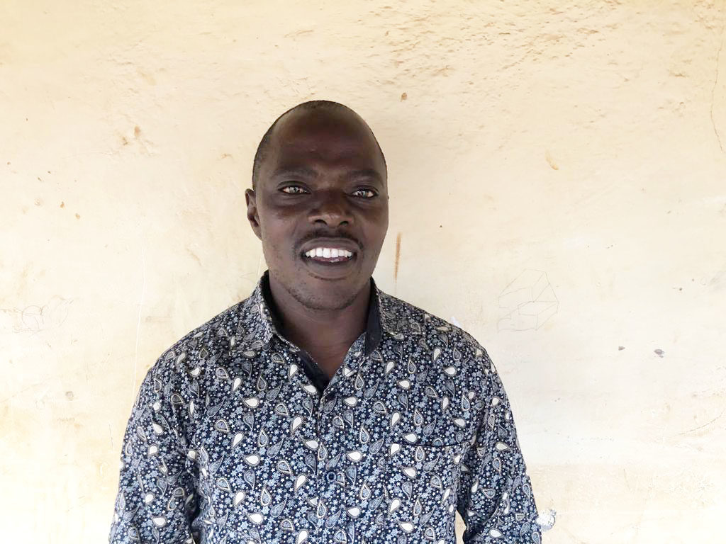 Kizito standing in front of a wall, looking at the camera