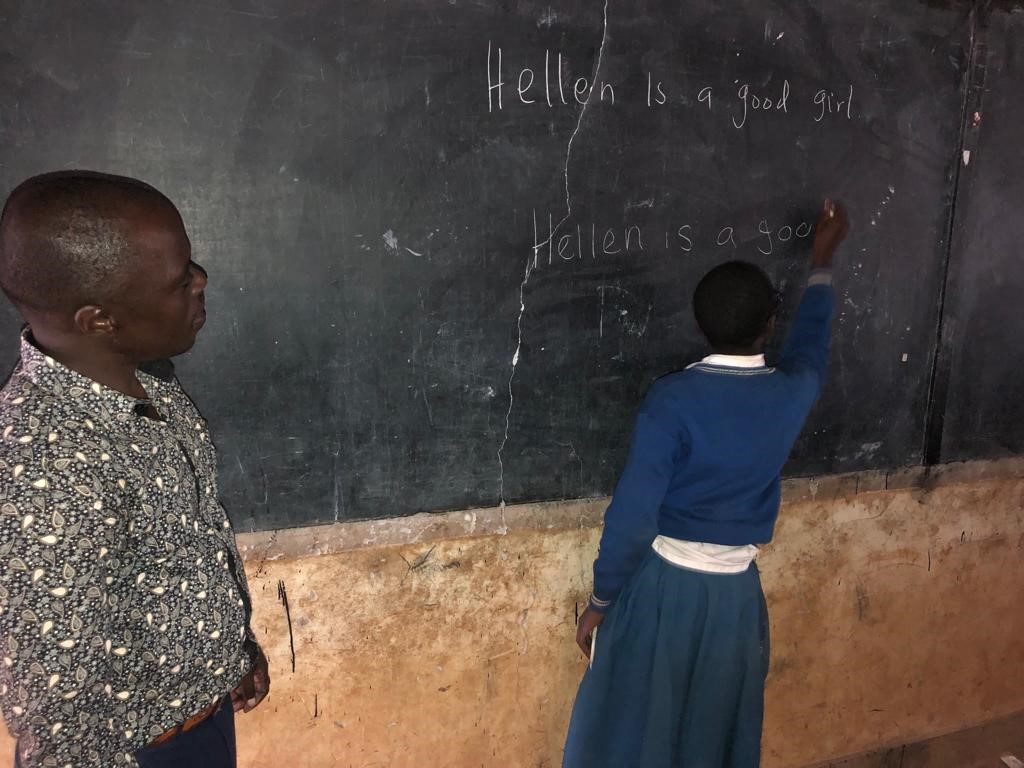 Kizito observes one of his students writing on the black board