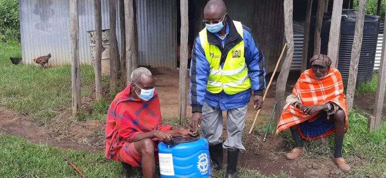 Blind man receives hand washing vessel from public health officer in Narok