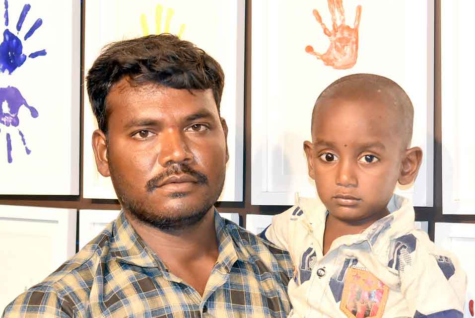 A father, holding his son, looking at the camera