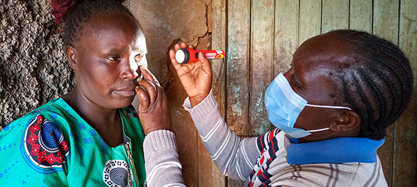 Woman examines another woman's eye