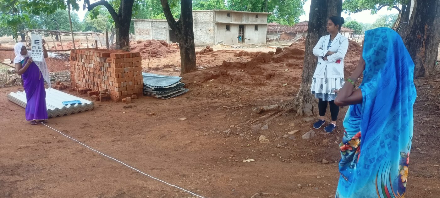 A community health worker checks the eyesight of a community member using an eye chart.