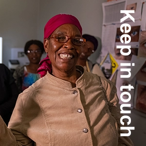 A senior woman, wearing eyeglasses, smiles at the camera