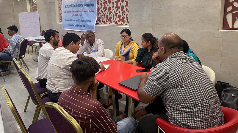 A group of women and men sit around a table having a discussion. 