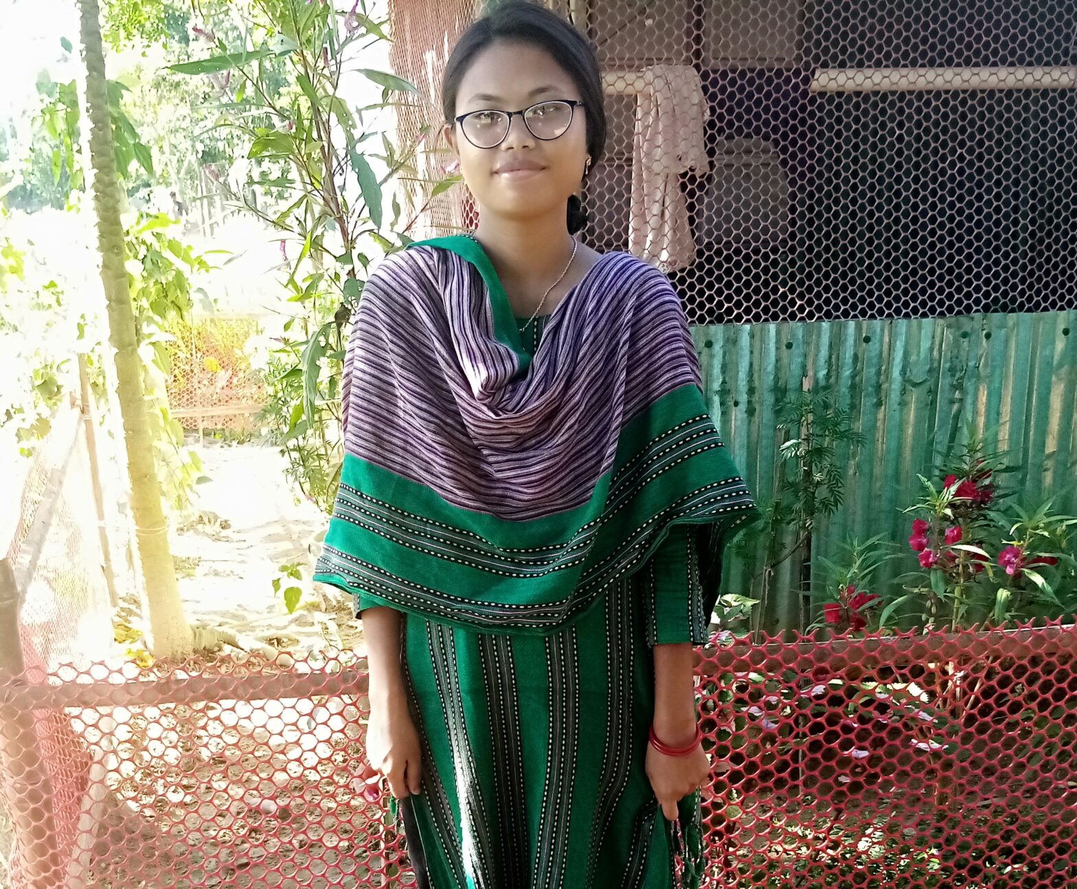 Woman from Bangladesh wearing a green sari smiles for the camera, sporting her prescription eyeglasses.
