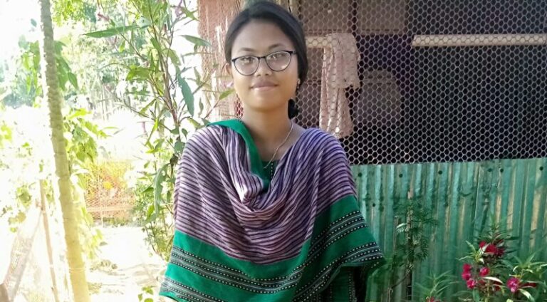Woman from Bangladesh wearing a green sari smiles for the camera, sporting her prescription eyeglasses.