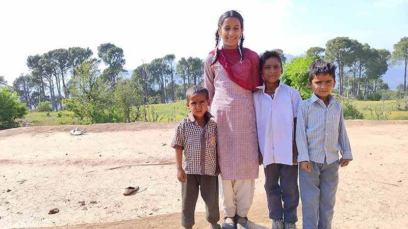 A young girls stands with three younger brothers.