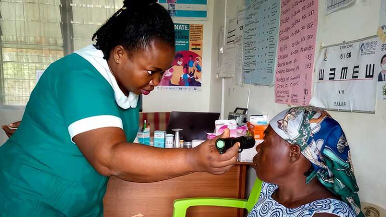 Woman examines the eye of a female senior with a small light.
