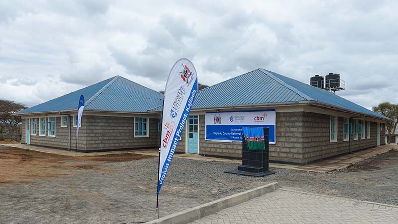 Two grey buildings with blue roofs. 