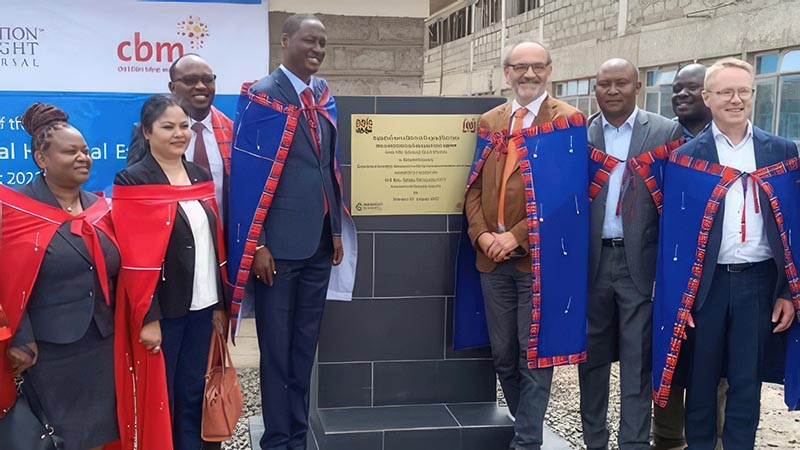 Group of people stand in front of a gold plaque.