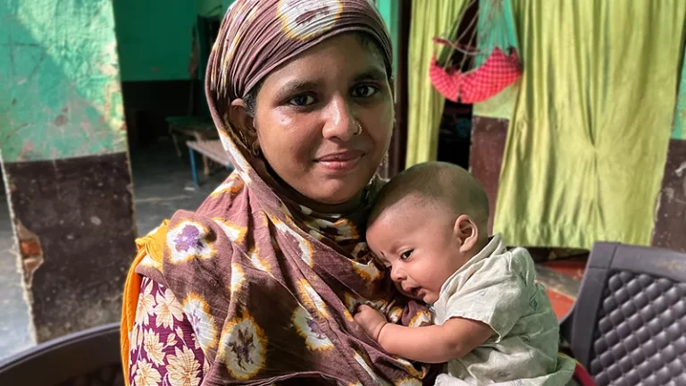 A woman hugs a small baby close her to chest.