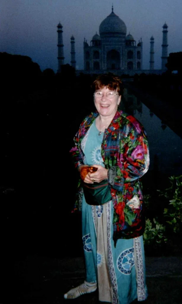 A woman standing in front of the Taj Mahal at dusk.