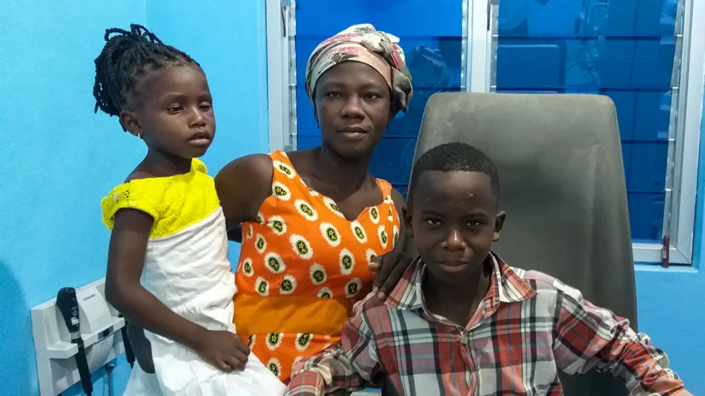 A woman, teenage boy and small girl pose for a picture in clinic. 