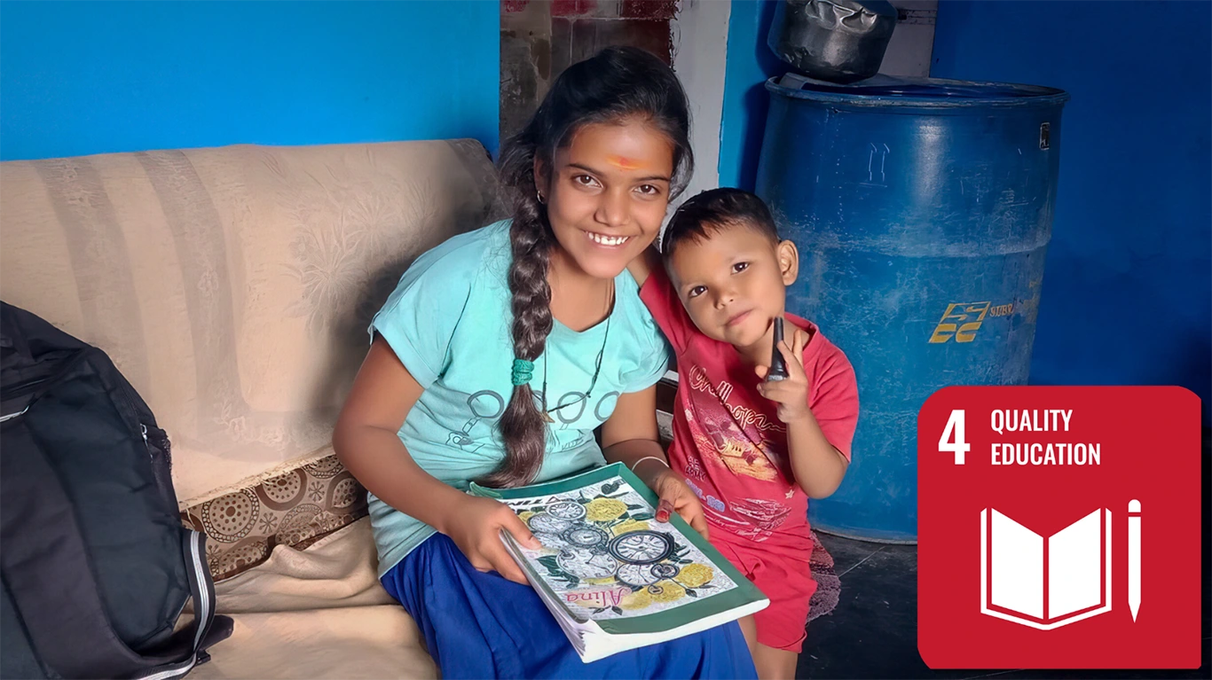 A young girl poses with her younger brother, a book on her lap. They are smiling.