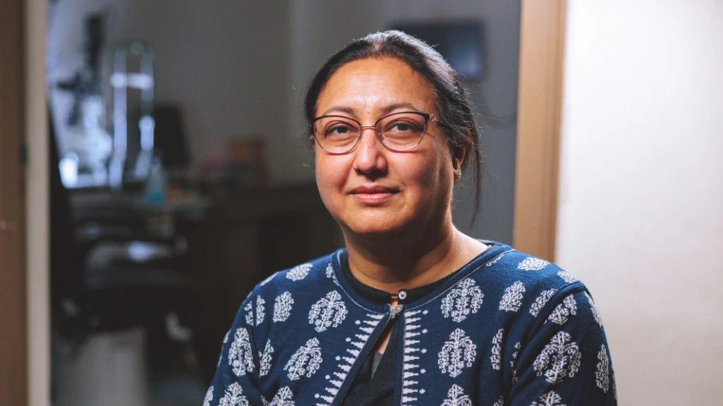A woman wearing a blue sweater is sitting in an office