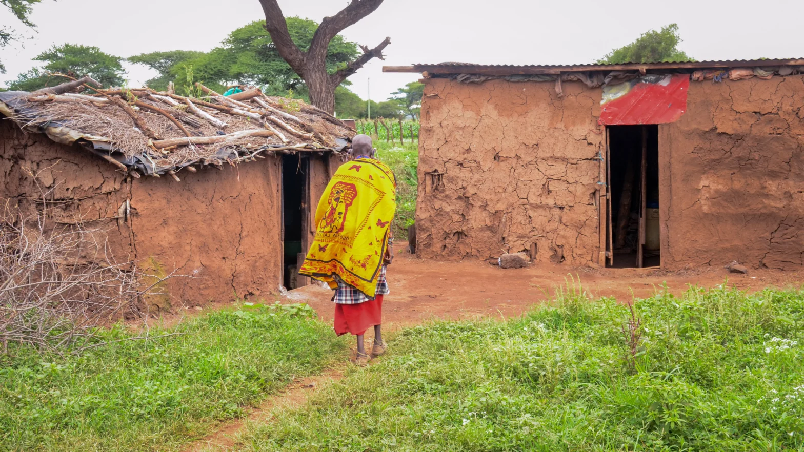 A woman walks towards a house in a village.