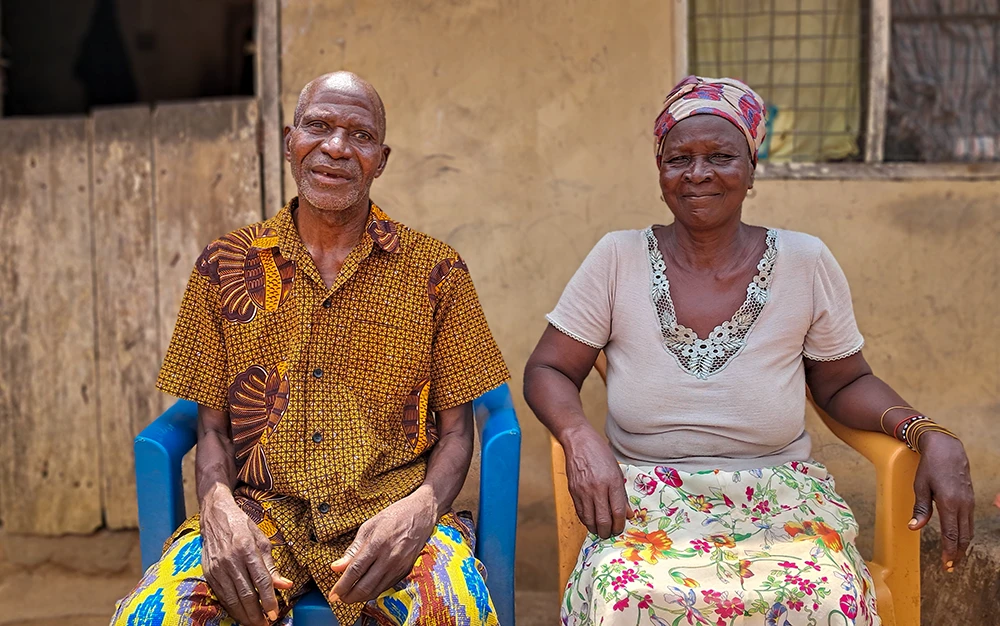 Close-up of Ayetu, an elderly man, with his wife, Adwoa, sitting in the shaded side of his one-room home in Adawukwa Fianko, Ghana.