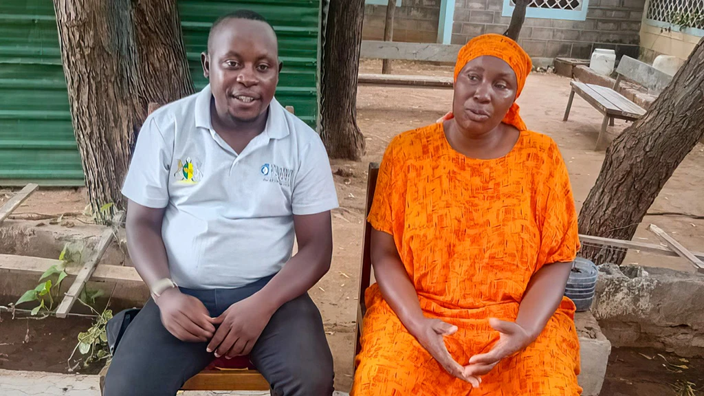 A man and a woman sit on an outdoor bench together.