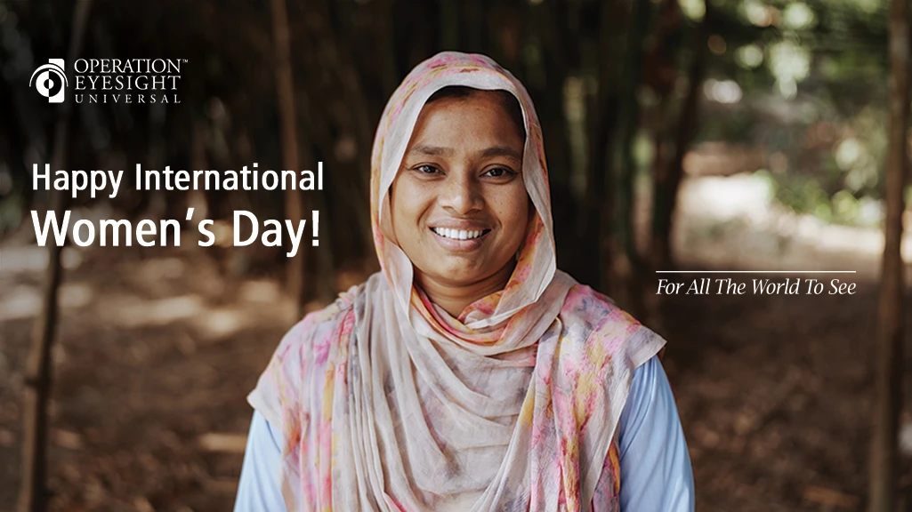 A young woman wearing a pink head scarf stands outdoors, smiling at the camera.