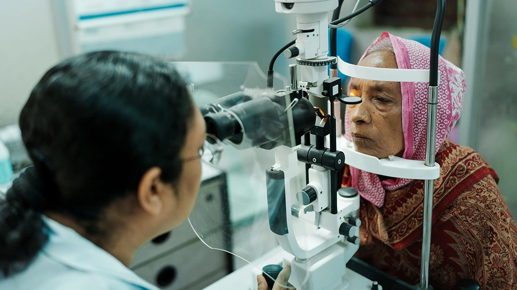 A health worker checks a woman's eyes through a slit lamp at a hospital in Bangladesh.
